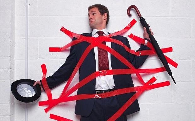 Businessman holding an umbrella and bowler hat stuck to a wall with red tape...BC49YM Businessman holding an umbrella and bowler hat stuck to a wall with red tape